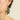 Green leaf-shaped earring worn by a person on a neutral background