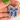 Hand-held close-up of blue botanical painting and gold-coloured accents on a porcelain bow pendant