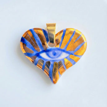 Heart-shaped pendant with blue eye design on a light gray background