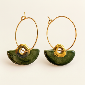 Pair of forest green porcelain hoop earrings with gold details on a warm ivory background