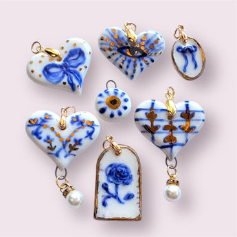 Latest Collection featuring a variety of elegant porcelain pendants, including heart shapes with intricate designs and gold accents, perfect for showcasing unique style.