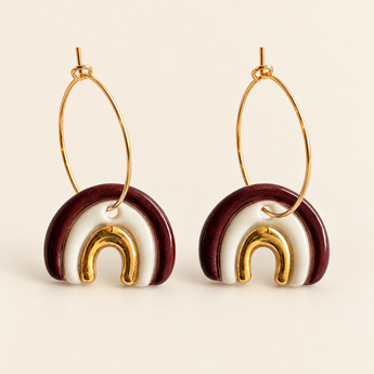 Burgundy and white porcelain rainbow hoop earring with 22K gold lustre worn on a model's ear