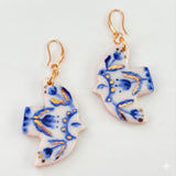 Pair of earrings with blue and gold floral design on a white background