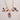 Close-up of hand-painted ceramic charms on gold necklace, showing dove, coral, medallion, and fish detail