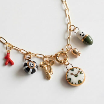 Whimsical porcelain charm necklace with clock, smiley face, and bow charms
