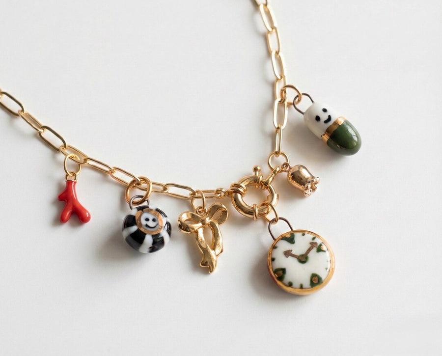 Whimsical porcelain charm necklace with clock, smiley face, and bow charms