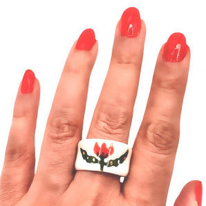 Handmade white porcelain ring with a red tulip design, worn on the middle finger of a hand with red polished nails. The ring has a smooth texture, wide band, and minimalist aesthetic, showcasing its artisanal, hand-painted floral artwork.