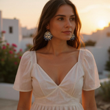 A model showcasing the Midnight Moonface hand-painted porcelain earrings by BitaJewells against a picturesque sunset backdrop. These striking gold earrings feature a delicate moon face, symbolizing artisan craftsmanship in beautiful ceramic jewelry. Perfect as a gifted piece for a girlfriend, they are lightweight and elegant, making them ideal for everyday wear and unique valentine gifts.